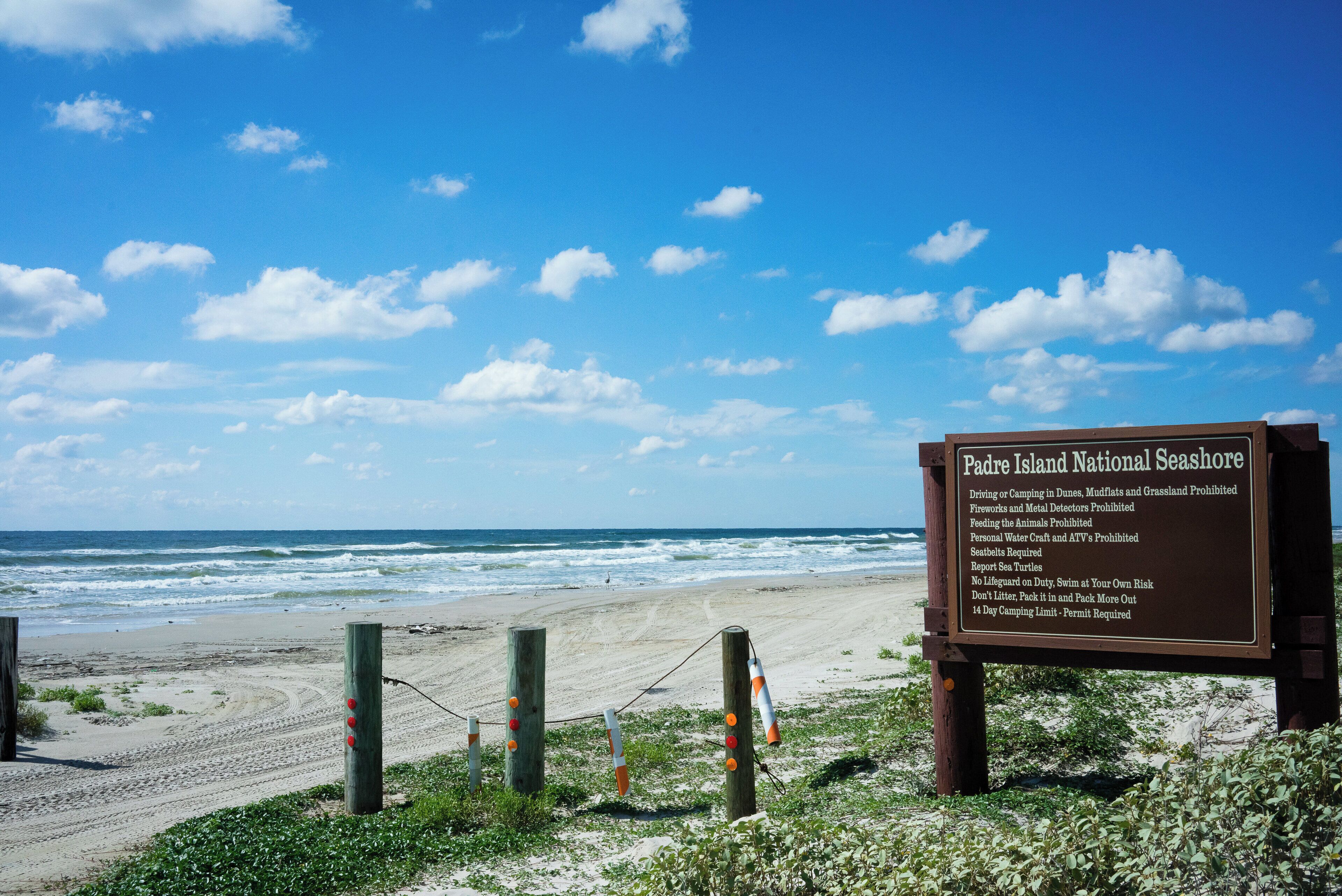 Una playa con un cartel que detalla normas y regulaciones.