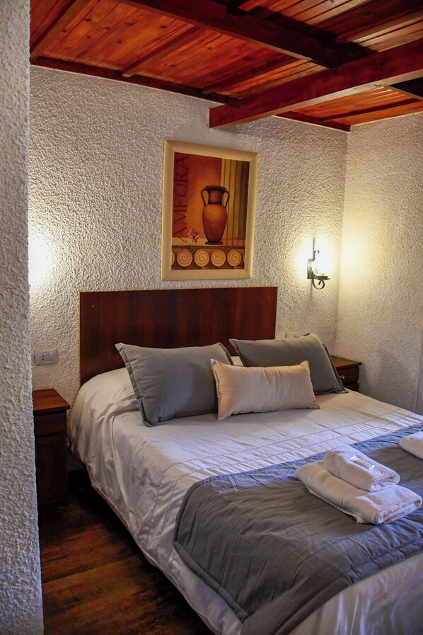 Une chambre à coucher avec une tête de lit en bois, un tableau au-dessus du lit et une table de chevet avec une lampe.
