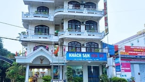 Ein mehrstöckiges Gebäude mit einem Schild, auf dem „KHÁCH SAN HOA ĐỘ“ und „HOADÔ HOTEL“ stehen, das ein Hotel kennzeichnet.