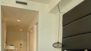 Une chambre à coucher avec un lit, une table de chevet, une lampe suspendue et une chaise.