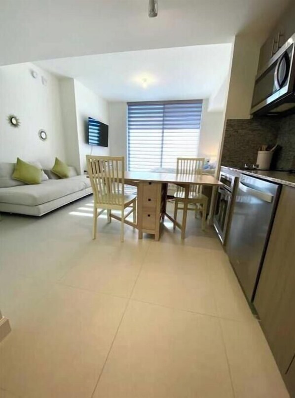 A compact kitchen with a dining area, a sofa, and a TV. - A1510 BRAND NEW Downtown Doral Studio (Doral)