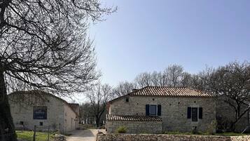 A stone building with a tiled roof, a gravel driveway, and a sign indicating 'Les Fortielles.'