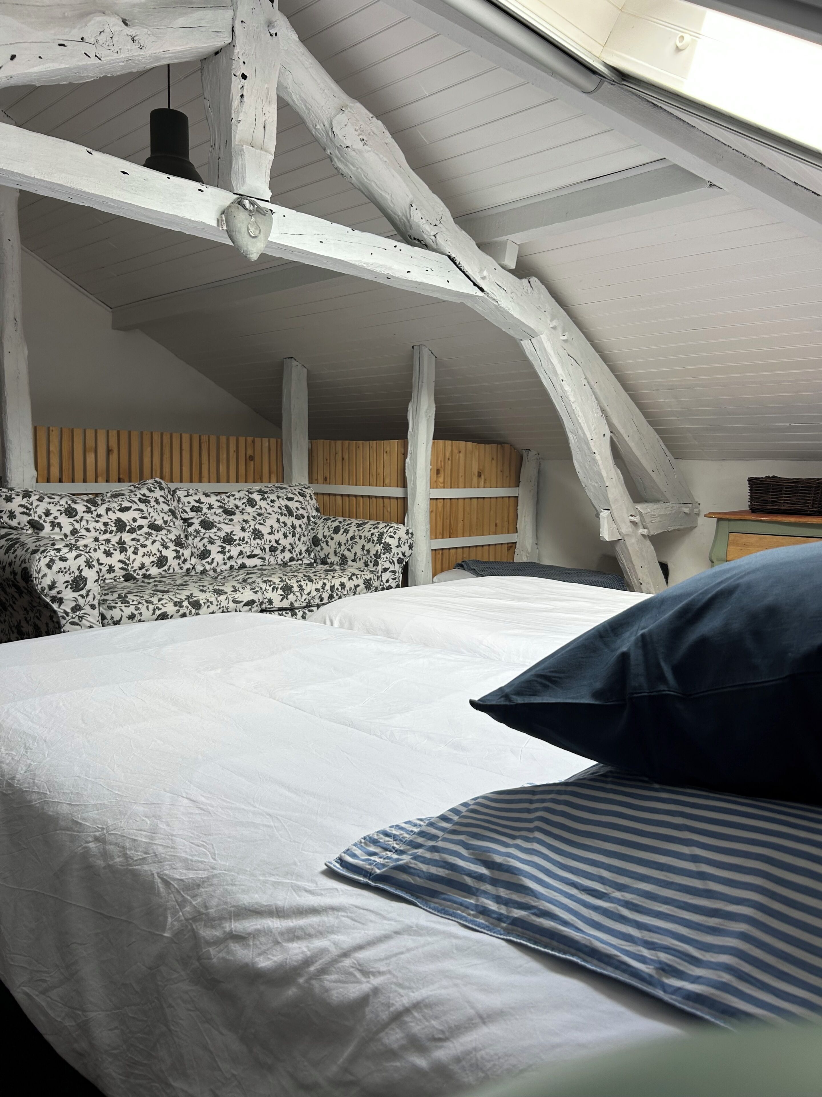 Et værelse med en seng, et træhovedgærde, et skråt loft og et vindue.
