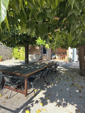 Un espace extérieur aménagé avec une table et des chaises, entouré de gravier et d’arbres.