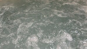 Un bain à remous rempli d’eau, un plafond en bois et un mur avec un miroir.