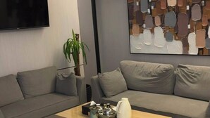 A modern living room with two sofas, a coffee table, a flat-screen TV, and abstract art on the wall. - Tallaq hotel (Madinah)
