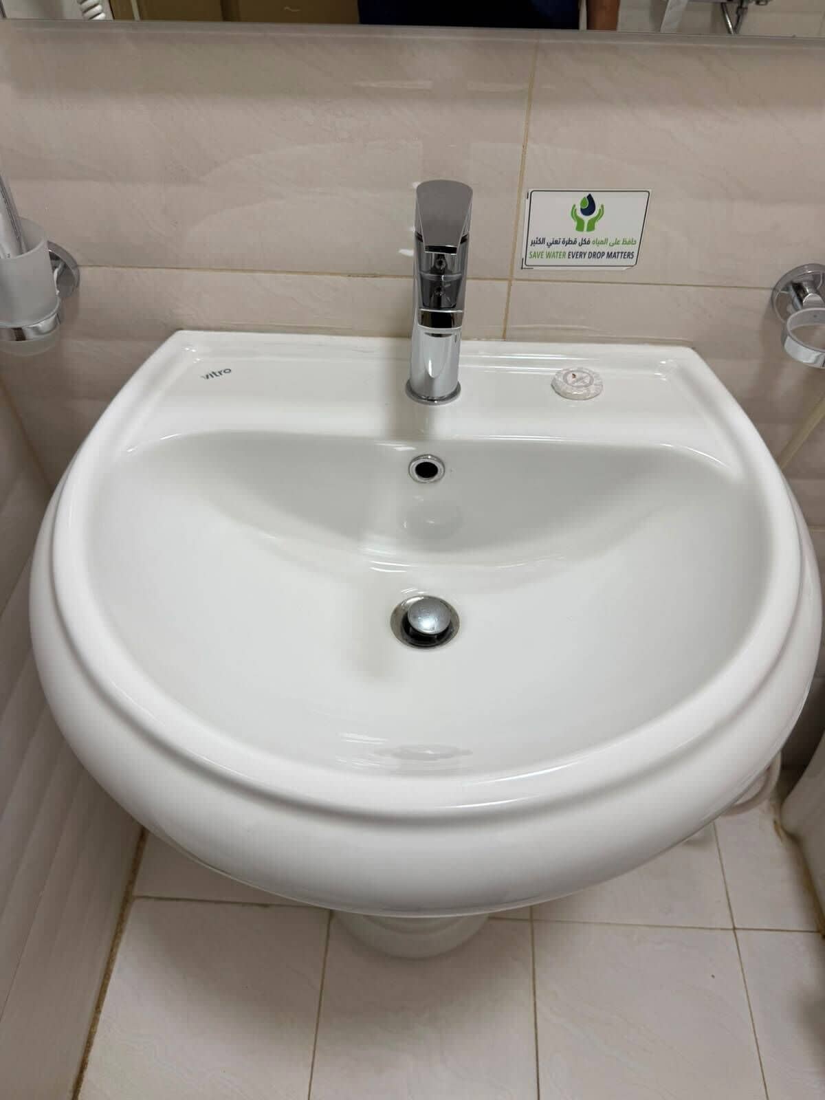 Un lavabo sur pied, de couleur blanche, doté d’un robinet chromé et d’un drain.