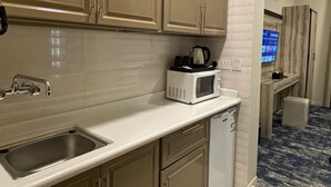 A compact kitchen with beige cabinets, a stainless steel sink, a microwave, and a dishwasher. - Tallaq hotel (Madinah)
