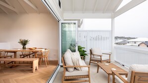 Un balcone con tavolo, sedie e divano in legno.