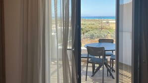 A room with a view of a table and chairs outside, a wooden ceiling, and a window with sheer curtains. - Latramys Suites (Naxos)