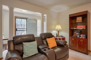 A living room with a leather recliner, a lamp, and a wooden cabinet with board games.