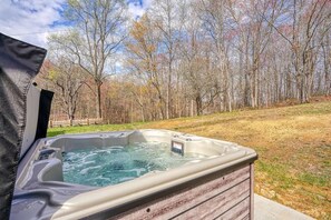 A hot tub with a wooden exterior, surrounded by a grassy area and trees.