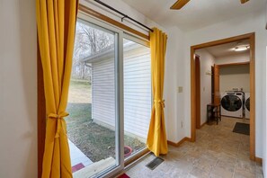 A room with a sliding glass door leading to a backyard, a washing machine, and a small table. - Ranch retreat in the heart of Hocking Hills (South Bloomingville)