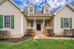 A two-story house with a front porch, a small entryway, and a staircase leading to the front door.