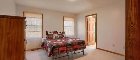 A bedroom with a bed, a wooden wardrobe, and a door leading to another room.