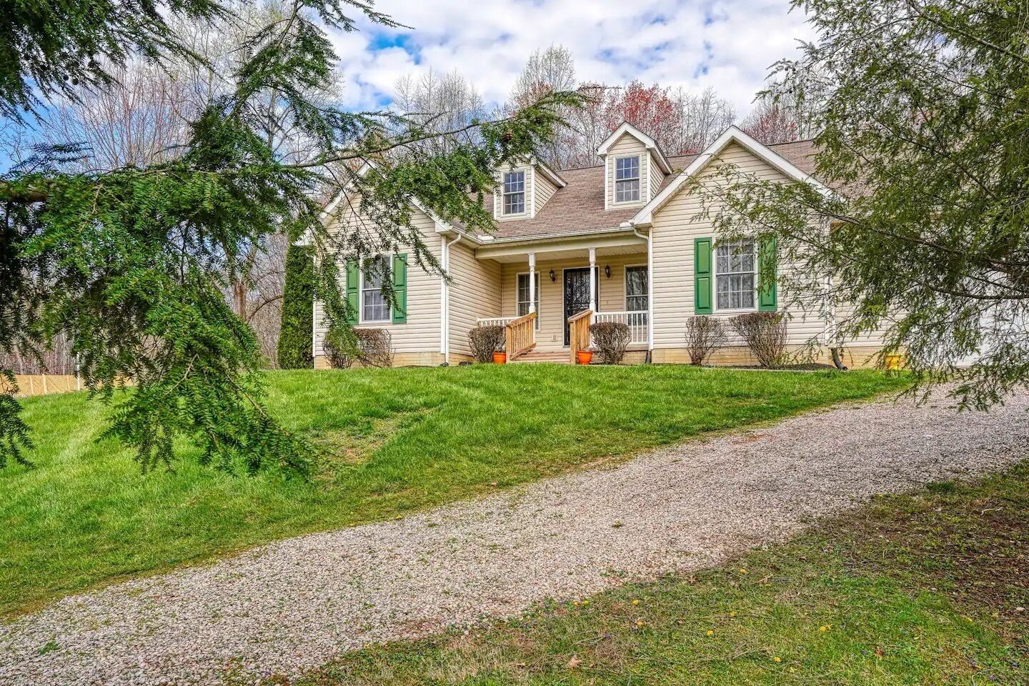 Une maison à deux étages avec un porche à l’avant, une allée et une pelouse bien entretenue.