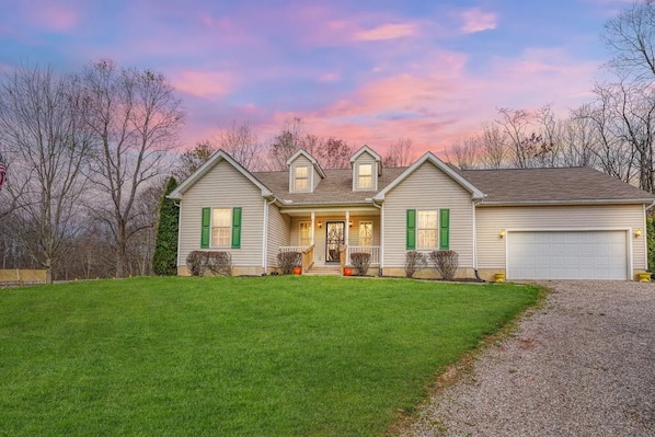 A two-story house with a front porch, a garage, and a well-maintained lawn.