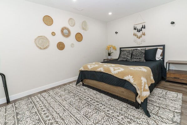 Une chambre à coucher moderne avec un lit, des tapis à motifs et des éléments de décoration murale.