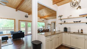 A spacious kitchen with wooden cabinets, a granite countertop, and a dining area with a sofa and table. - Muskoka Riverside Retreat on the Indian River in the heart of Port Carling (Port Carling)