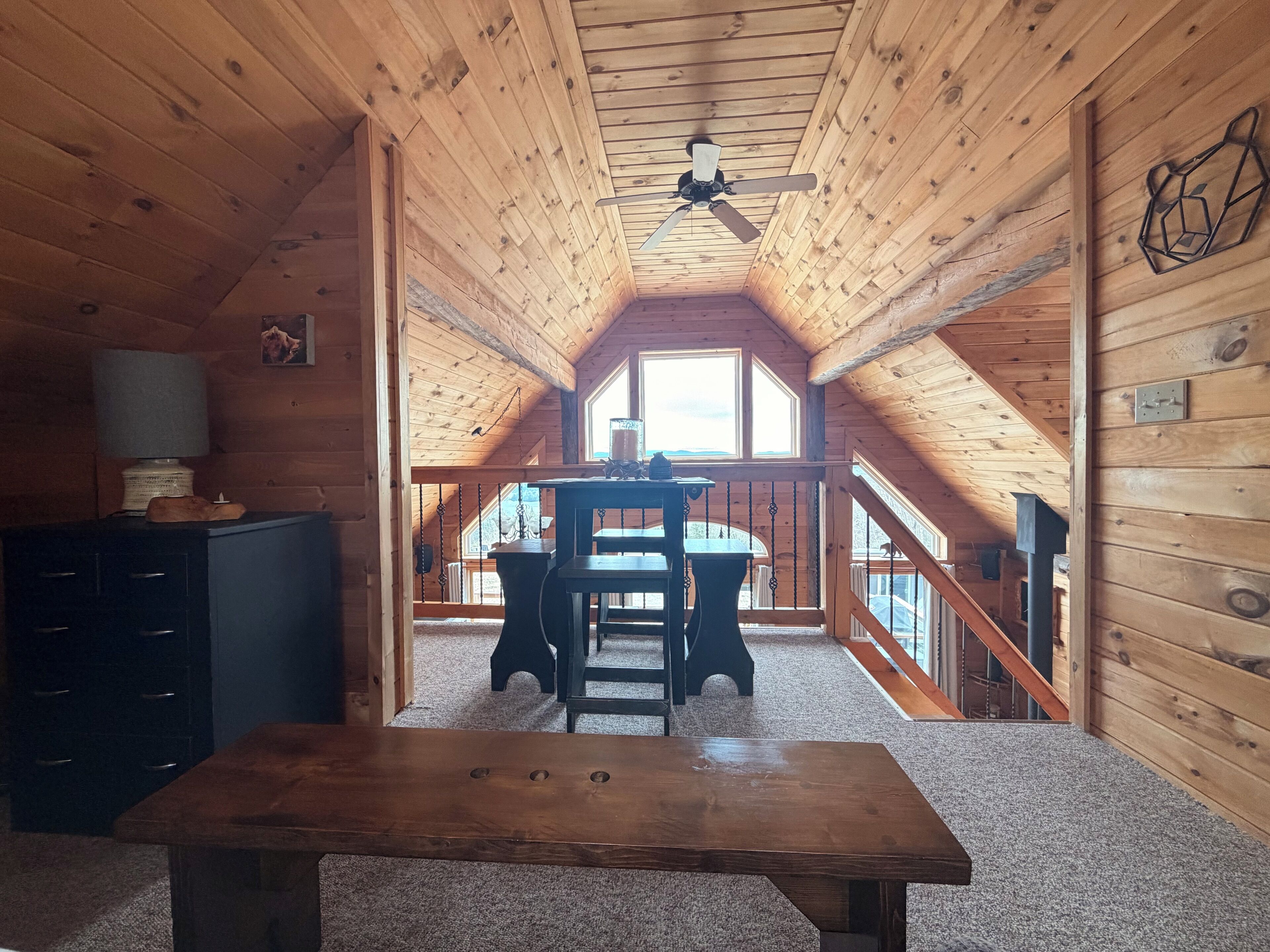 Un intérieur en bois avec une table à manger, un ventilateur de plafond et une vue par la fenêtre.