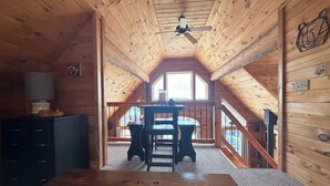 A wooden interior with a dining table, a ceiling fan, and a view through a window. - Your Perfect Mountain Escape-Cozy Cabin Retreat. (Errol)