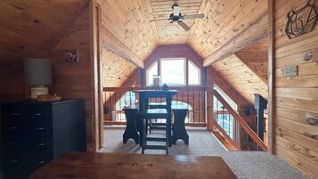 Un intérieur en bois avec une table à manger, un ventilateur de plafond et une vue par la fenêtre.