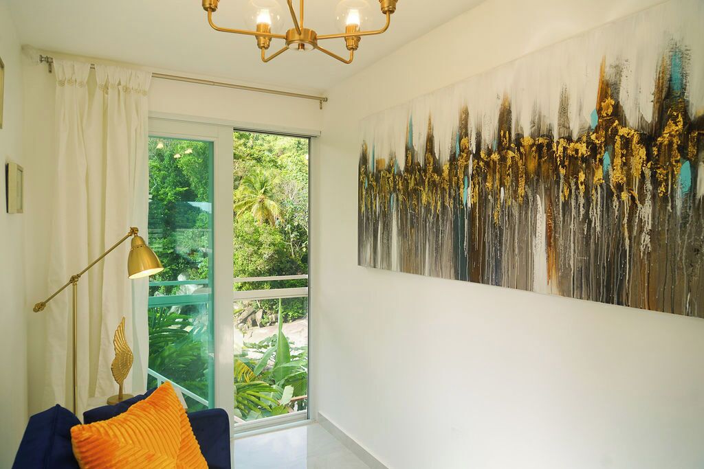 A room with a large window, a modern chandelier, and a large abstract painting on the wall.