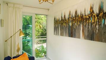 A room with a large window, a modern chandelier, and a large abstract painting on the wall.
