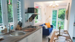 A modern kitchen with a wooden countertop, a sink, and a built-in stove. There is a blue sofa with orange cushions in the adjacent living area. - El Yunque Rainforest (Naguabo)