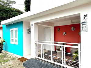 Welcome to a vibrant home with a white and turquoise exterior, featuring a cozy balcony and inviting entrance.