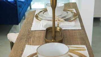 A dining table set with white plates, gold-rimmed bowls, and a candle holder.