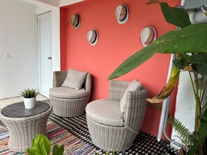 Relax in this serene outdoor seating area with two cushioned chairs and a small table.