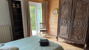 Un dormitorio con cama, armario, silla y vistas a zonas verdes.