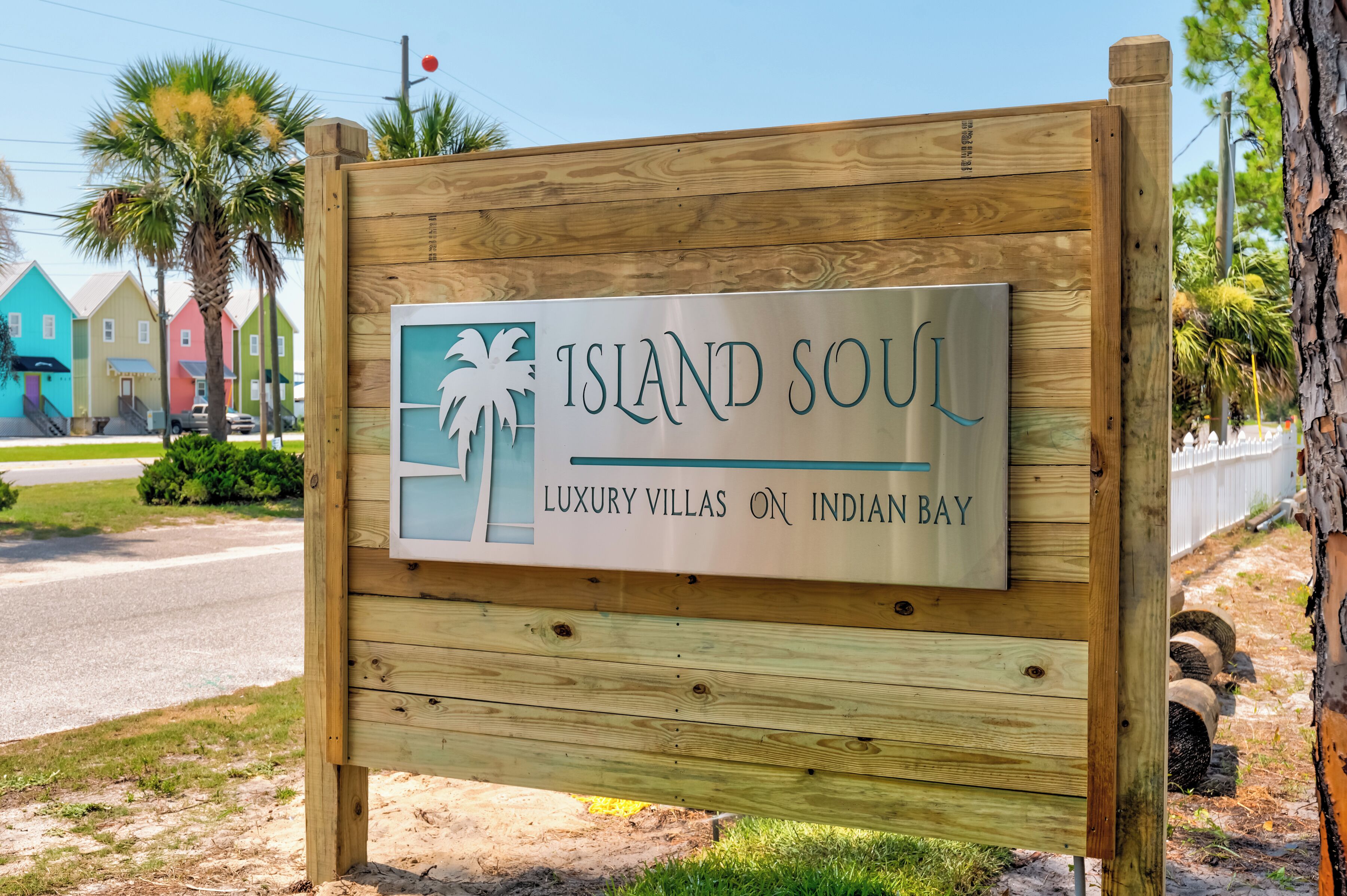 A wooden sign with 'ISLAND SOUL' and 'LUXURY VILLAS ON INDIAN BAY' text, indicating a resort area.