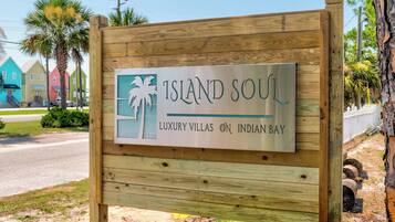 A wooden sign with 'ISLAND SOUL' and 'LUXURY VILLAS ON INDIAN BAY' text, indicating a resort area.