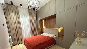 A modern bedroom with a bed, wooden headboard, bedside tables, and a small table with a bottle. - Tashkent City Boulevard (Tashkent)