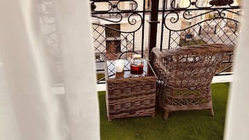 Un balcón con muebles de mimbre y una pequeña mesa, con vistas a una zona residencial.