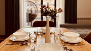 A dining table set with white plates, glasses, and cutlery, centered with a vase of flowers. - Tashkent City Boulevard (Tashkent)