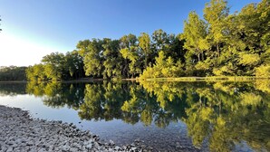 Un lac paisible aux eaux claires, où se reflètent les arbres, et dont les rives sont rocheuses.