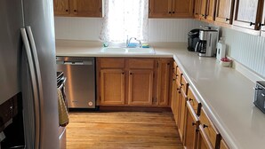 Une cuisine moderne avec des meubles en bois, un réfrigérateur en acier inoxydable et un lave-vaisselle encastré.