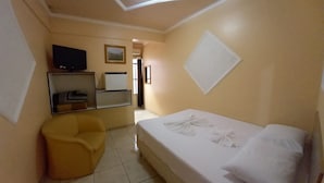 A hotel room with a bed, a TV, a mirror, and a yellow armchair. - Hotel São Luis  (Pinhao)