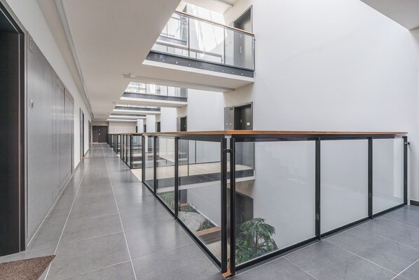 Ein modernes Interieur mit Glastrennwand, einem langen Korridor und einer hohen Decke mit Oberlichtern.