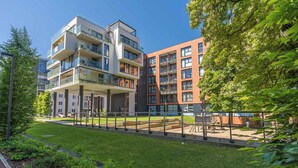 A modern apartment building with multiple balconies, a covered outdoor area, and a well-maintained garden. - Scala Premium by Grand Apartments (Gdansk)