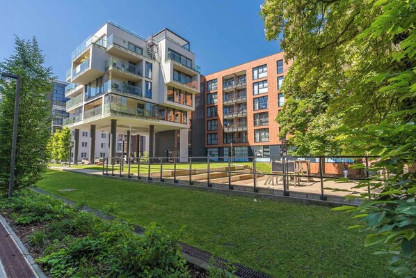 A modern apartment building with multiple balconies, a covered outdoor area, and a well-maintained garden. - Scala Premium by Grand Apartments (Gdansk)