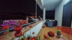 A balcony with a railing, a table with a potted plant, and a chair.
