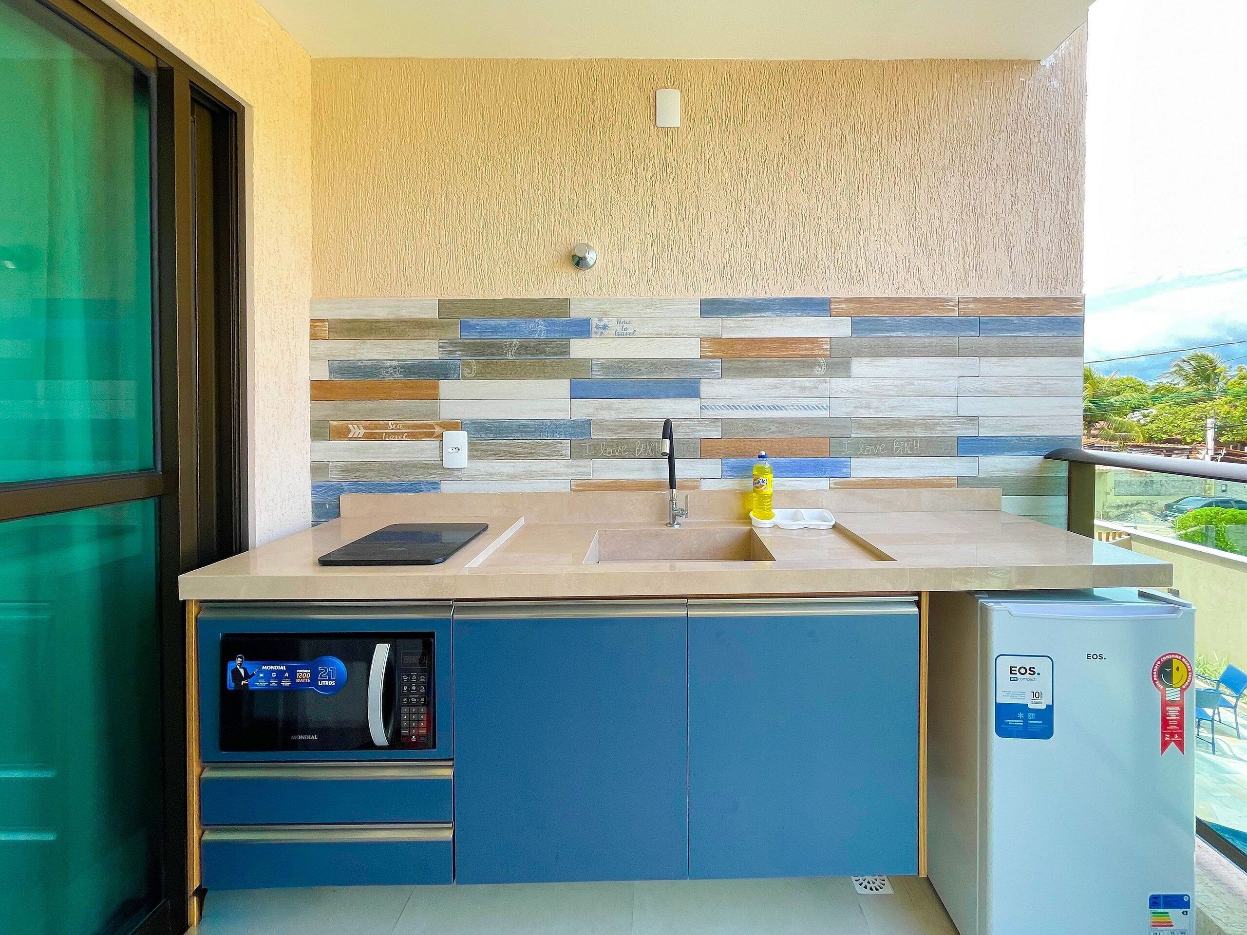 A compact kitchen with a microwave, sink, and a small refrigerator.