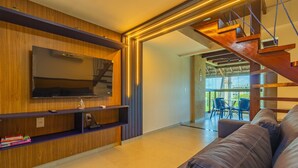 Un salon moderne avec un téléviseur à écran plat, des étagères en bois, un canapé en cuir et un escalier.