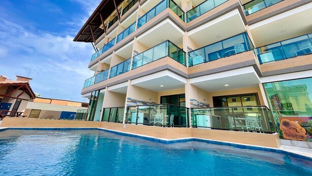 Un hôtel à plusieurs étages, doté de balcons, d’une piscine et offrant une vue sur un ciel dégagé.