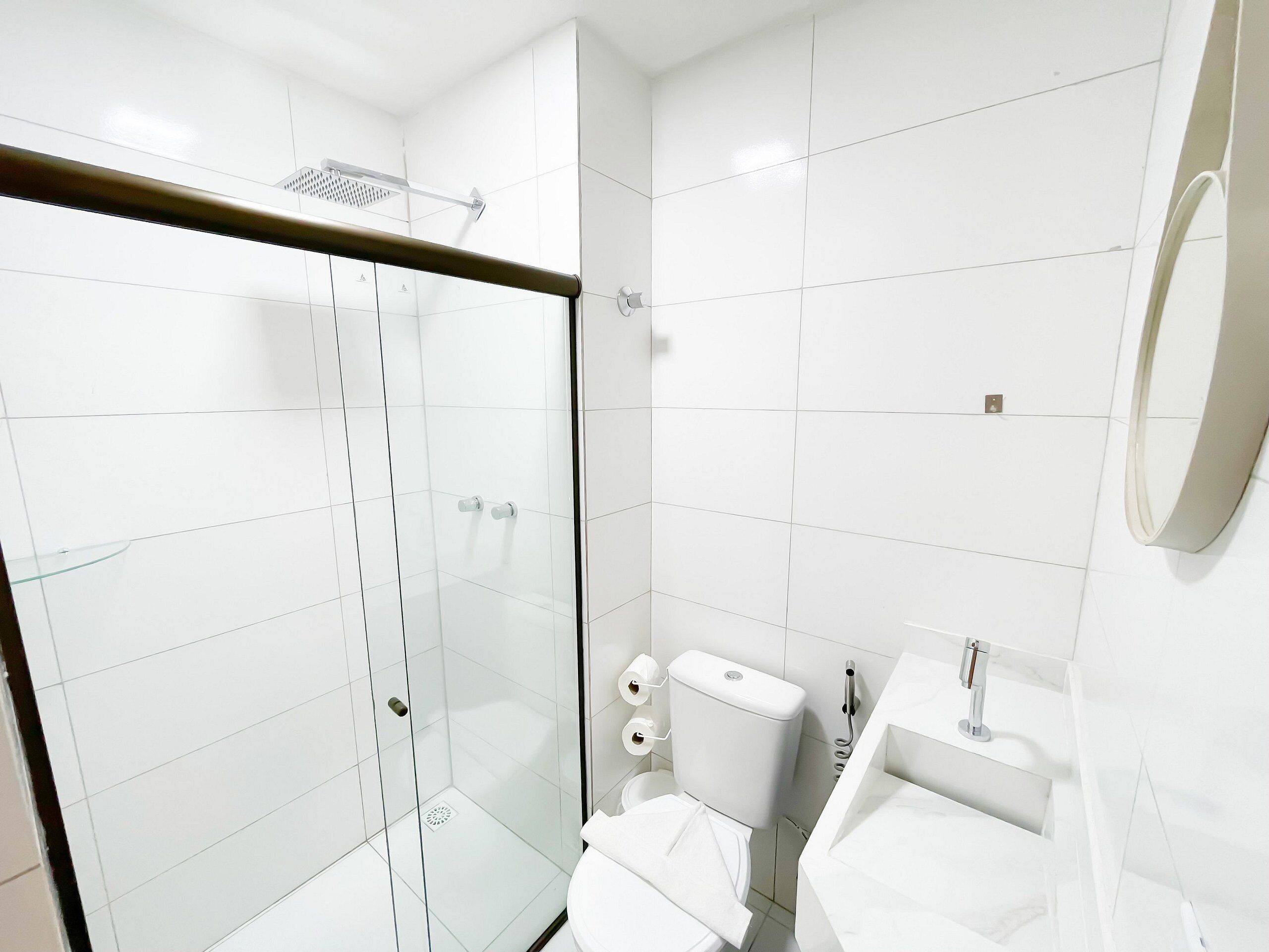 Un bagno moderno con cabina doccia in vetro, un water e un lavandino con specchio.