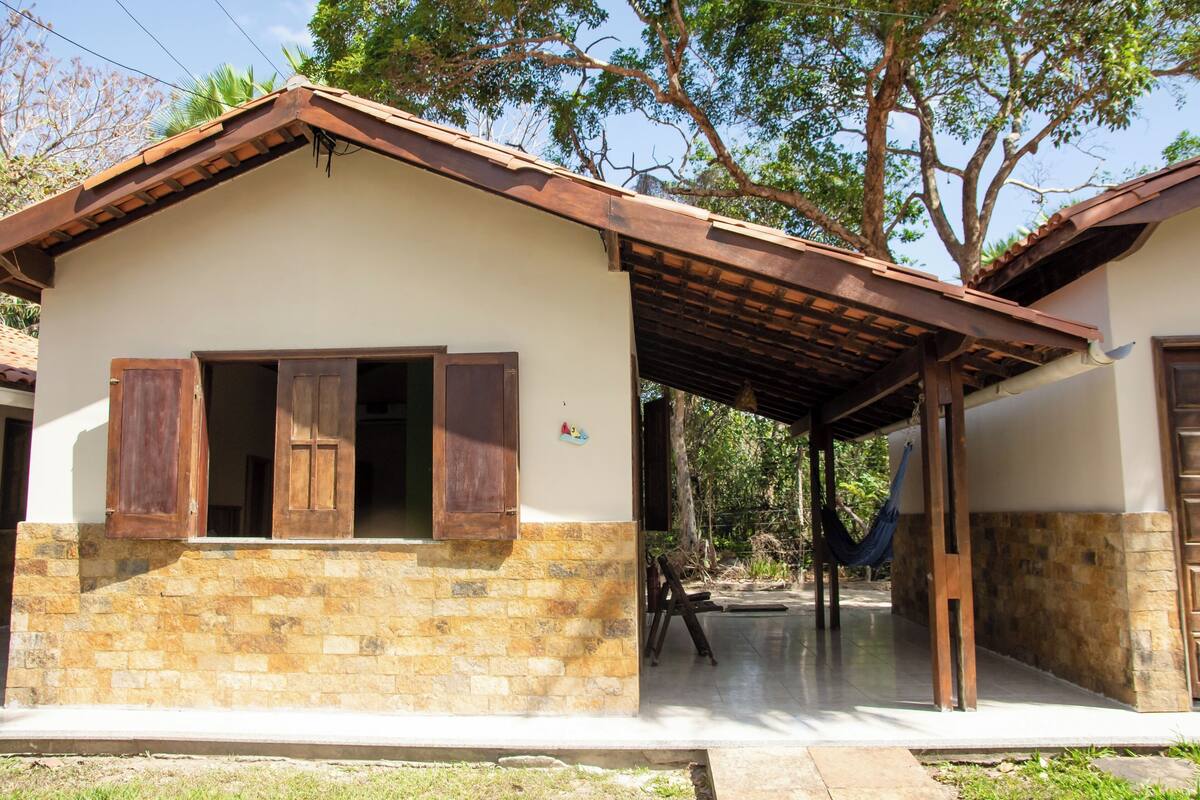 A house with a stone facade, wooden shutters, and a covered porch.